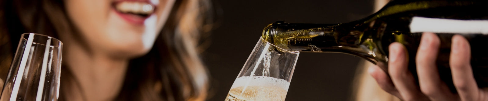 A person serving Champagne to another person illustrating the Champagne selection by Whelehans Wines.